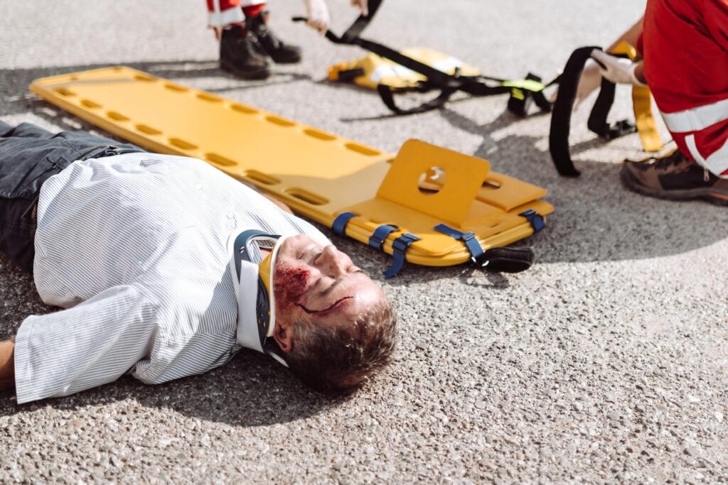 Equipe de resgate utiliza prancha amarela para imobilizar paciente ferido.
