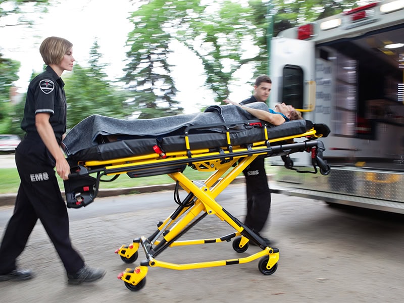 EMS personnel transport a patient on a wheeled stretcher into an ambulance for urgent medical care.