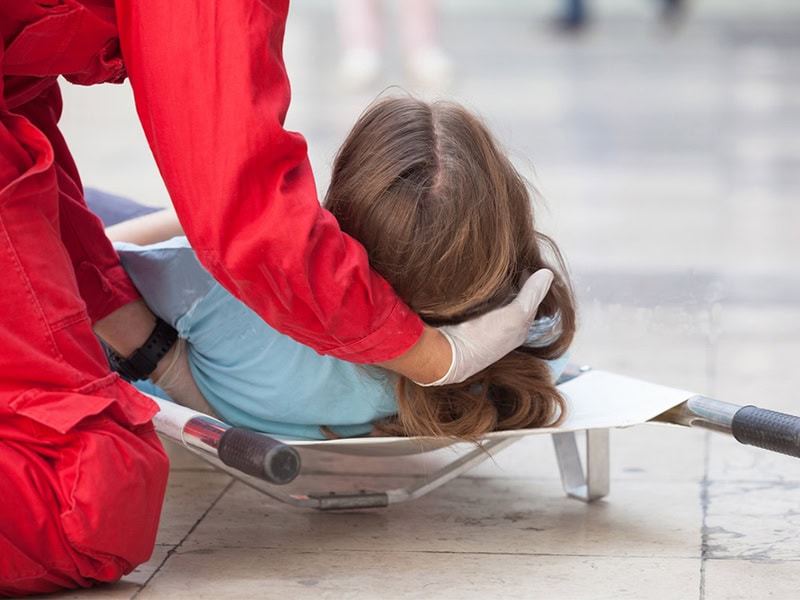 Emergency responder stabilizes a patient's neck on a scoop stretcher during rescue.