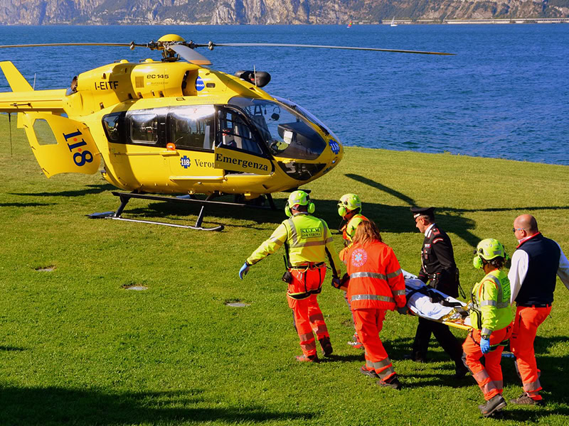 Emergency responders carry a patient on a stretcher to a rescue helicopter for urgent medical evacuation.