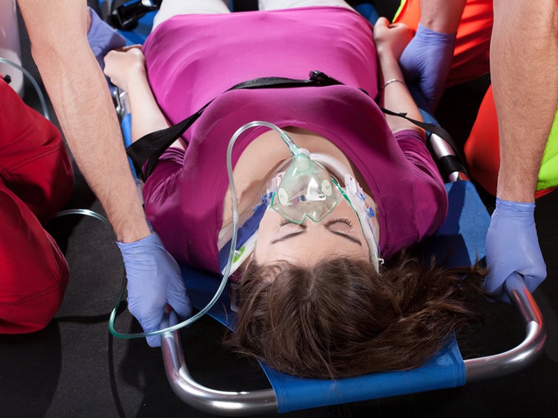 Injured woman receiving oxygen support while secured on a stretcher during emergency medical response.