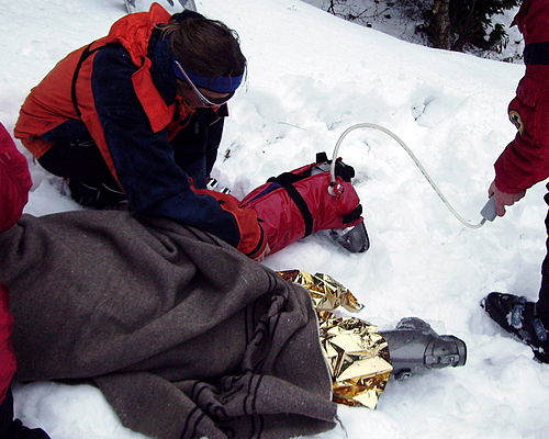 Mountain rescue using vacuum stretcher for injured skier in cold weather
