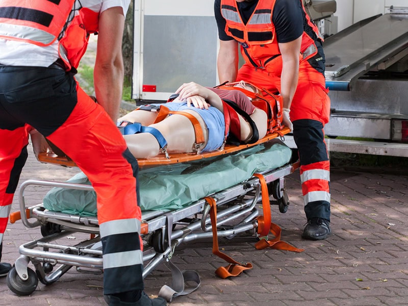 Rescue team transfers an injured patient from spine board to ambulance stretcher for safe emergency transport.