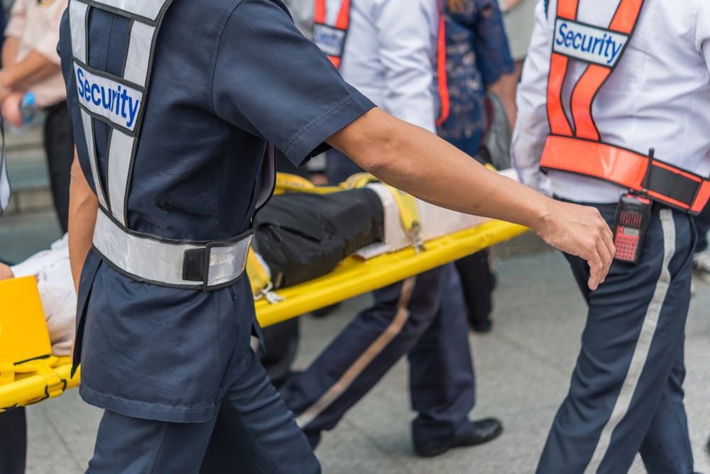 Personal de seguridad transporta a una persona herida en una camilla amarilla.