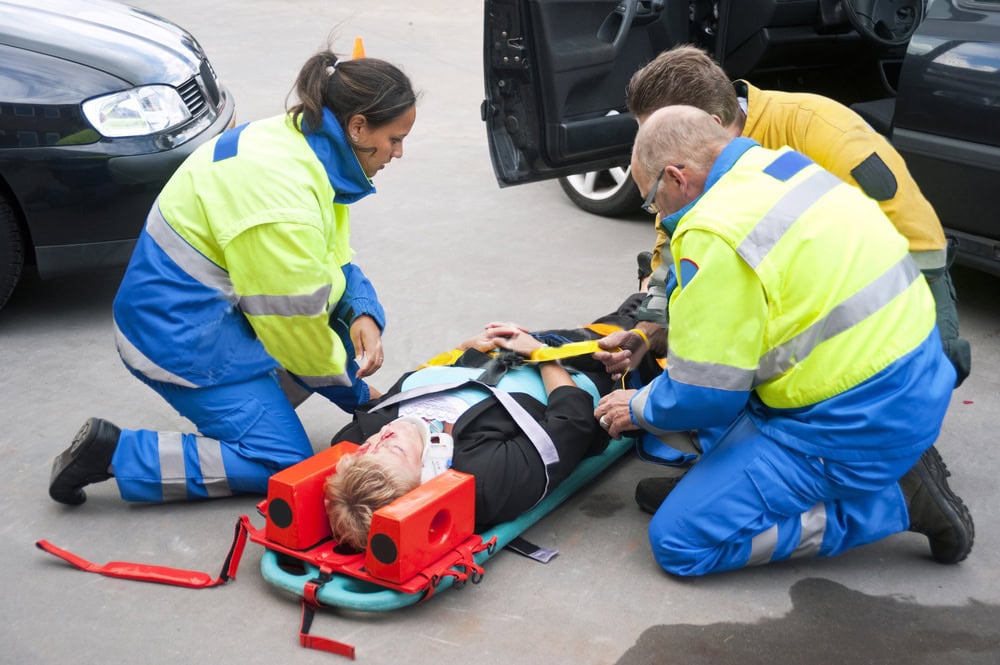 Paramedics secure a patient with a head immobilizer after a car accident