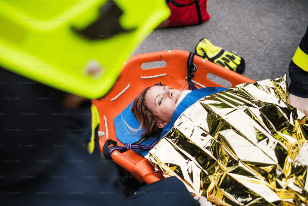 Patient stabilized on stretcher with neck support and foil blanket