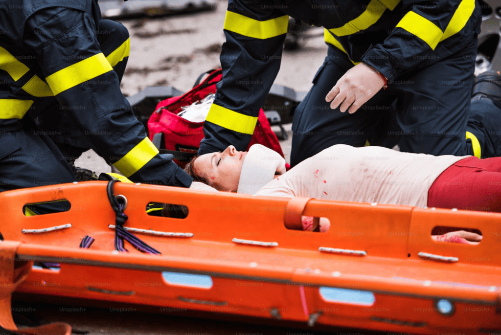 Firefighters assist injured woman on orange rescue stretcher