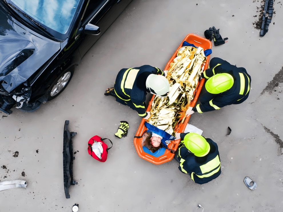 Emergency responders using orange basket stretcher to transport crash victim