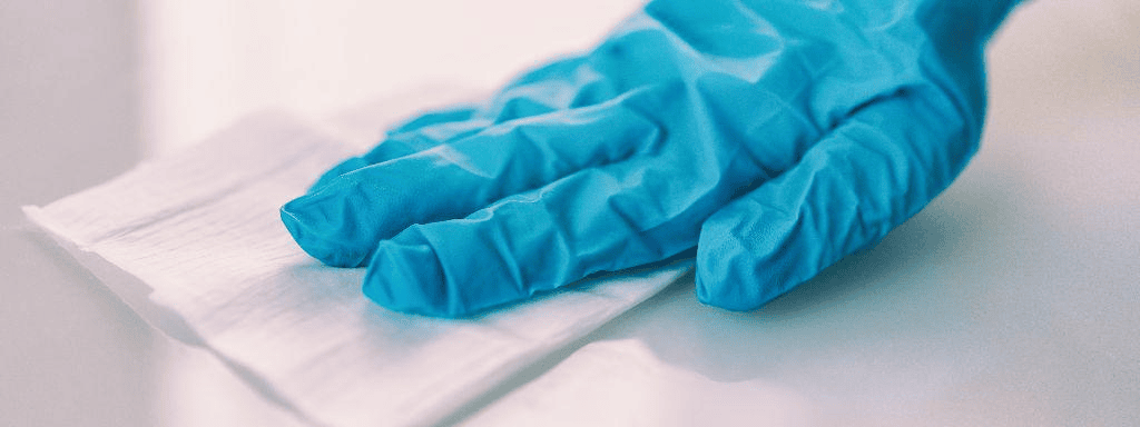 Gloved hand holding medical wipe