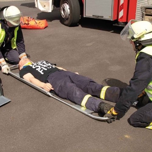 Firefighters placing injured man on scoop stretcher during emergency rescue